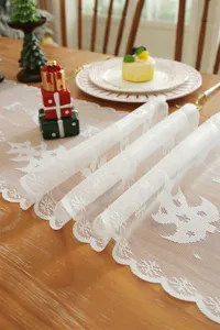 Camino de mesa de encaje blanco con patron festivo de copos de nieve para decoracion navideña.