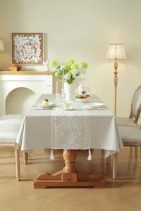 Detailed view of the modern minimalist white lace embroidered table runner with delicate tassels.