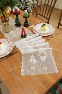 Camino de mesa navideño de encaje blanco con bonitos diseños de campanas y copos de nieve.
