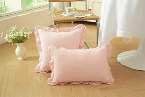 Cojín decorativo rosa con volantes y borde de encaje fino, estilo campestre francés.