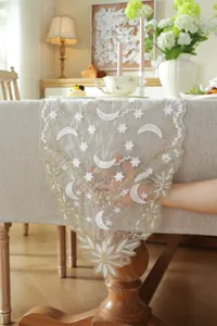 White and gold star moon embroidered lace table runner detail, showing sheer floral pattern.