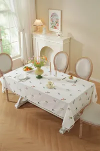 Detailopname van het geborduurde katoenen tafelkleed met bloemen en franjes, gezellig interieur.
