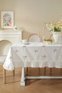 Detailed view of the elegant cotton floral embroidered tablecloth in a cozy dining setting.