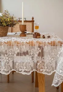 Dettaglio tovaglia ricamata in pizzo bianco francese con motivi floreali intricati e trama elegante.