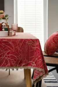 Detailed view of red and gold jacquard tablecloth with elegant lace edging for home decor.