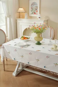 Gedetailleerd overzicht van het katoenen geborduurde tafelkleed met bloemen en kwastjes.