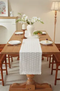 Detaillierte Ansicht des weißen Spitzen-Tischläufers auf Holztisch mit schöner Blumendeko.