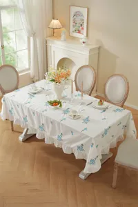 White cotton embroidered floral tablecloth with elegant ruffle edge, perfect dining table decor.