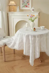 Vue détaillée d'une nappe en dentelle française blanche avec broderie florale exquise et bordure.