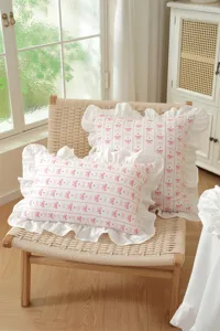 Detail shot of a French pastoral style ruffled throw pillow with cute pink bow pattern print.