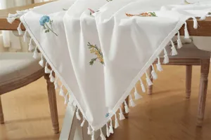 Gedetailleerd uitzicht op katoenen geborduurde tafelkleed met elegante franjes.
