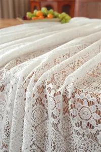 Primo piano dettagliato della tovaglia di pizzo bianco con eleganti motivi floreali.