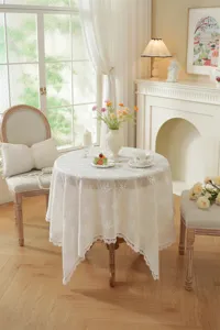 Détail de nappe en dentelle blanche française, broderie florale 3D élégante pour déco table.