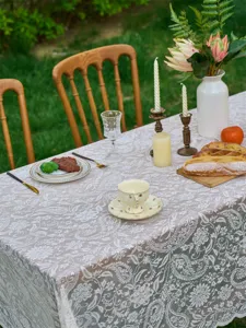 Outdoor French vintage lace tablecloth detail showing delicate floral patterns and texture.