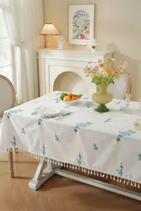 Elegante katoenen tafelkleed met blauwe bloemborduursel en franjes voor de eetkamerdecoratie.