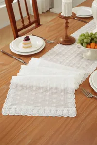Detailaufnahme des weißen Baumwoll-Spitzen-Tischläufers und der feinen Tischset-Details.