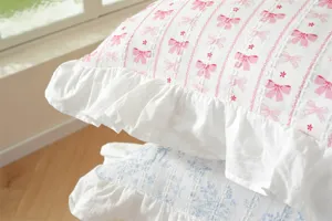 Close-up of French ruffle cotton pillowcase with cute pink bow and blue floral print.