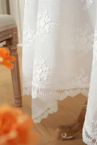 Vue détaillée d'une nappe en dentelle française blanche avec broderie florale exquise.