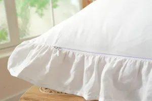 Detail shot of white cotton pillowcase featuring elegant ruffles and a hidden zipper.