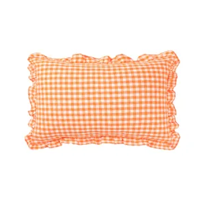 Close-up detail of orange gingham ruffled throw pillow, showing textured cotton fabric.
