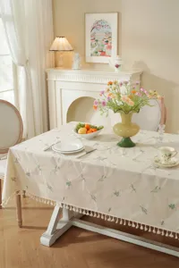 Close-up van geborduurde katoenen tafelkleed met bloemen en franjes voor gezellige eettafel decor.