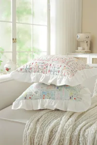 Close-up of French style floral patchwork throw pillow with white ruffle edge detail.