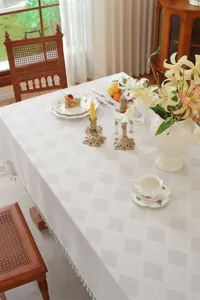 Weiße Tischdecke mit Quasten und Spitze im Detail, elegante Struktur für das Esszimmer.