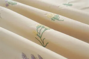 Katoenen geborduurde bloemige tafelkleed detail close-up met fijne plantenpatroon textuur.