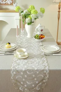 Detailed view of a luxurious white and gold star moon lace embroidered table runner for decor.