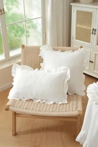 French country style white ruffled throw pillow cover detail in cozy home interior.