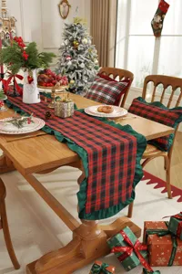 Christmas plaid table runner detail showing red and black pattern with green ruffled edge decoration.