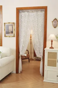 Detailed close-up view of elegant white floral lace door curtain showcased in a cozy home doorway.