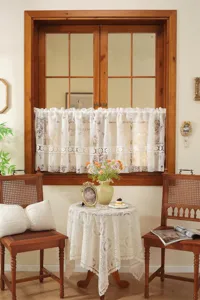 Détail de rideau court en dentelle française, design jacquard ajouré pour fenêtre de cuisine.
