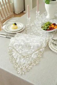 White gold embroidered lace table runner detail showing delicate star and moon pattern setup.