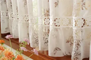 Gros plan détaillé d'un beau rideau en dentelle française blanche avec imprimé floral et ajouré.
