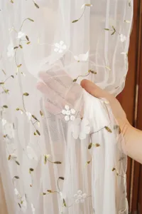 White sheer lace curtain detail, delicate floral embroidery, soft fabric, elegant room decor.
