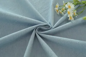 Vue détaillée de tissu en coton lavé bleu clair avec texture douce et accessoire de marguerite.