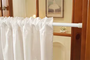 Close-up detail shot of white embroidered short curtain with tension rod for home door decor.