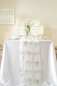 Detailed view of white vintage lace table runner with colorful flower embroidery and delicate text.