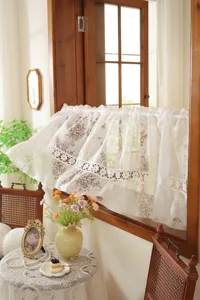 Detail du court rideau en dentelle de style vintage francais au motif floral delicat.