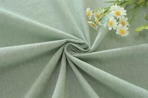 Gros plan détaillé d'un tissu en coton lavé vert clair avec une texture douce et beaux drapés.