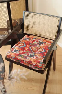 Close-up detail of the thick square seat cushion with ethnic geometric patterns on a wooden chair.