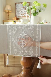 Modern white lace embroidered table runner with geometric floral pattern and elegant tassels.