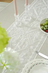 Elegant white lace table runner with floral embroidery for modern dining table decor.