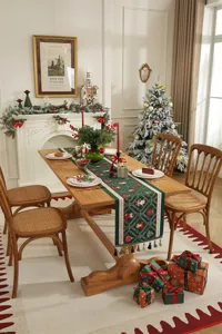 Primo piano del runner da tavola natalizio in jacquard verde con motivi festivi e nappe.