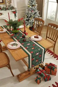 Dettaglio runner da tavola natalizio con motivi jacquard festivi e nappe su legno.