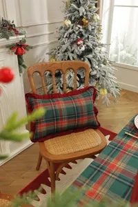 Christmas plaid table runner and ruffled cushion in cozy holiday scene detail view.