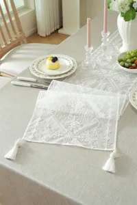 Elegant white lace table runner with floral embroidery and tassels for wedding home decor.