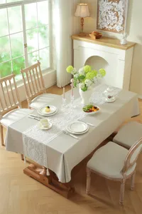 White lace embroidered table runner with tassels, elegant geometric design for dining room.