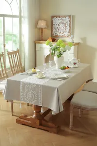 Elegant embroidered white lace table runner and tablecloth for dining room wedding decor detail.
